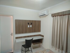 A room with a desk, chair, wall-mounted air conditioning unit, and a door. - Apartment Lacqua DiRoma IV - JC Temporada (Caldas Novas)