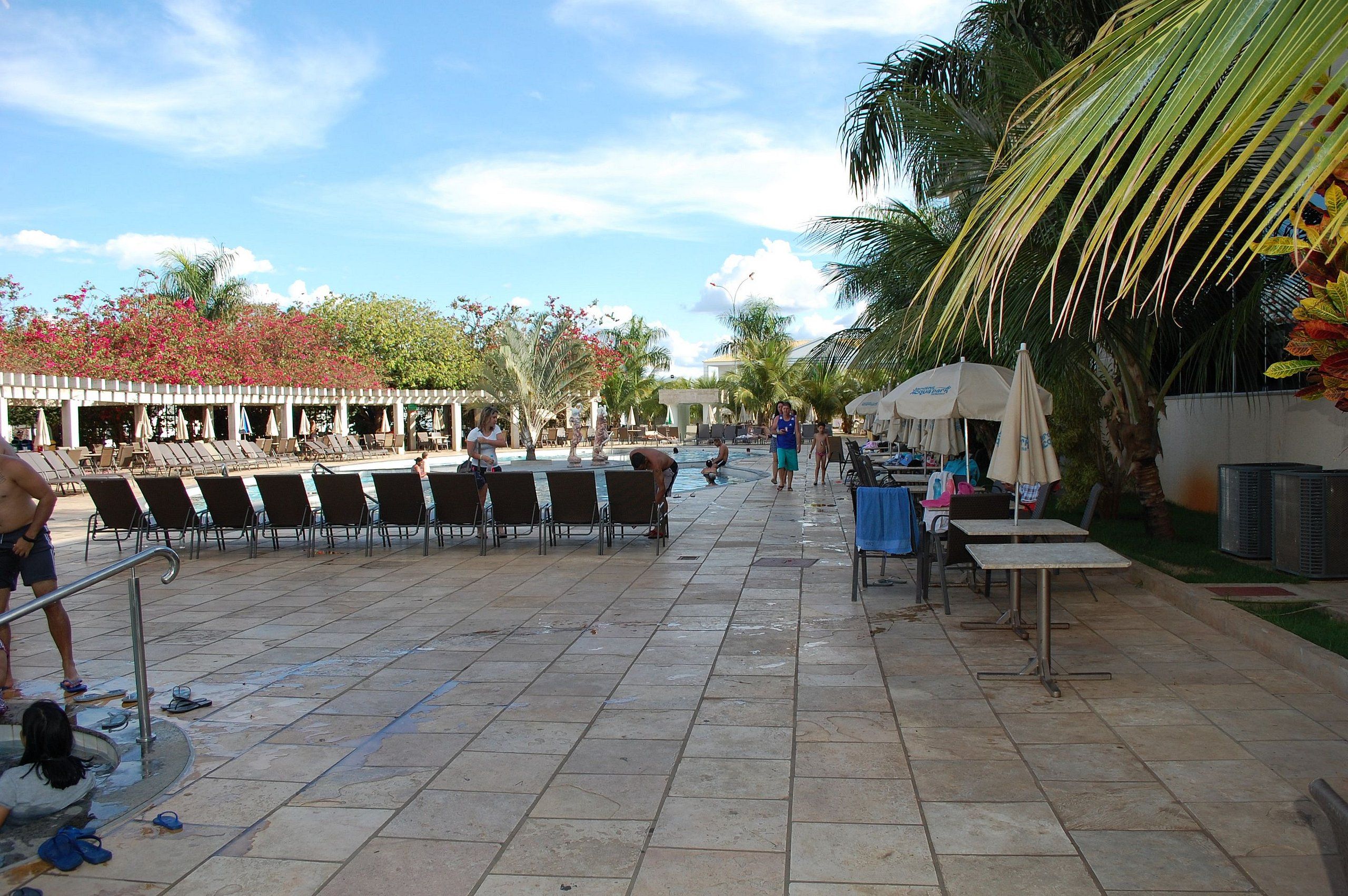 A poolside area with lounge chairs, umbrellas, and a covered seating area.