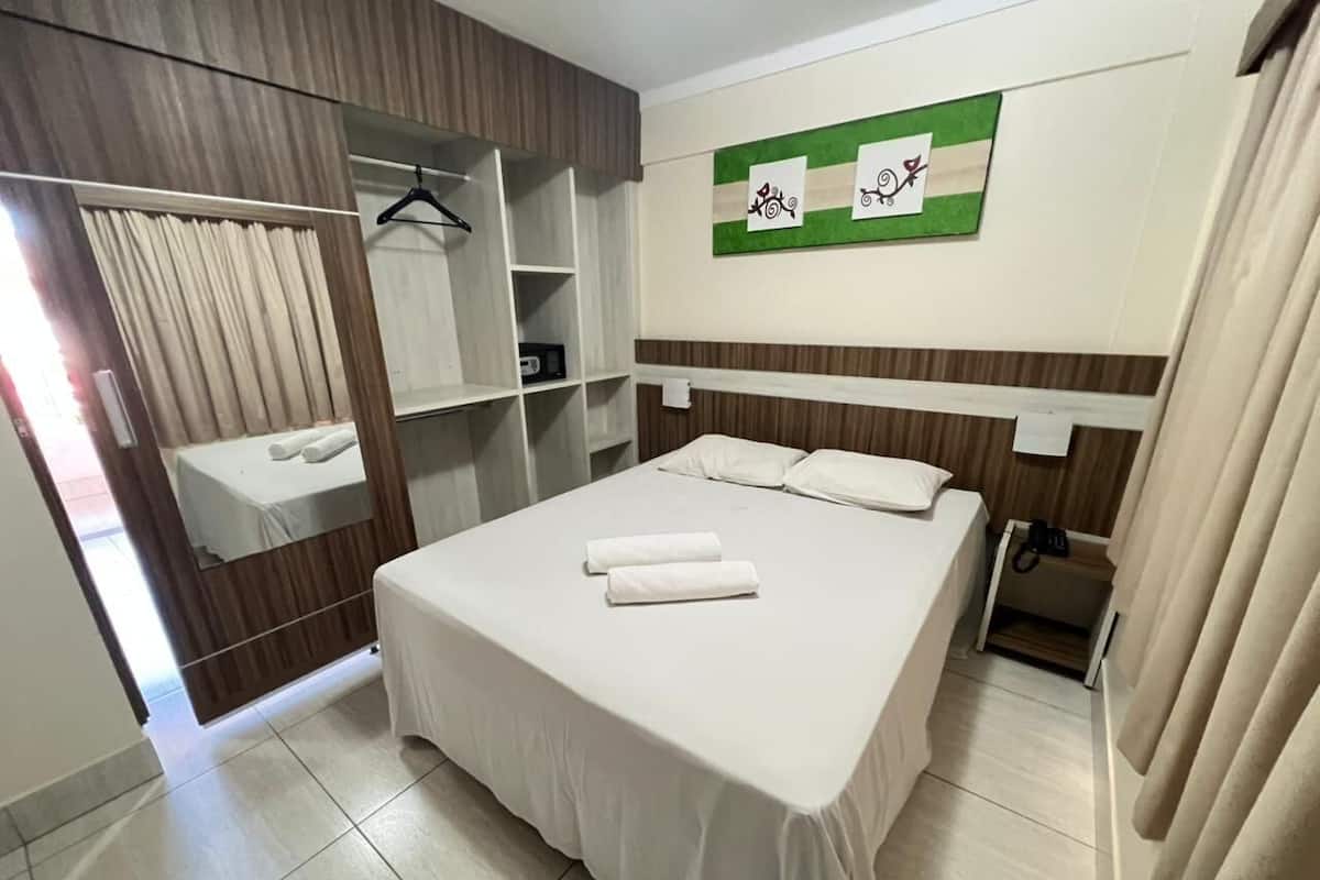 Ein Hotelzimmer mit Bett, Kleiderschrank, Spiegel und einer Wanddekoration in Grün.