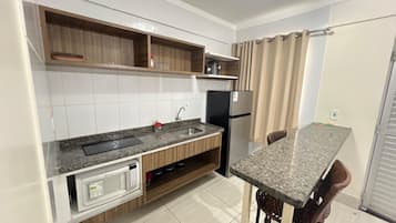 A compact kitchen with a built-in microwave, a sink, and a refrigerator.