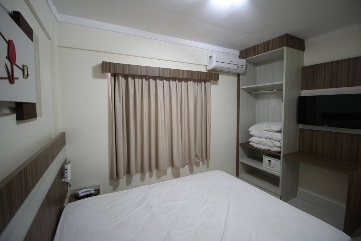 Une chambre d’hôtel équipée d’un lit, d’un appareil de climatisation, d’une télévision et d’une armoire.