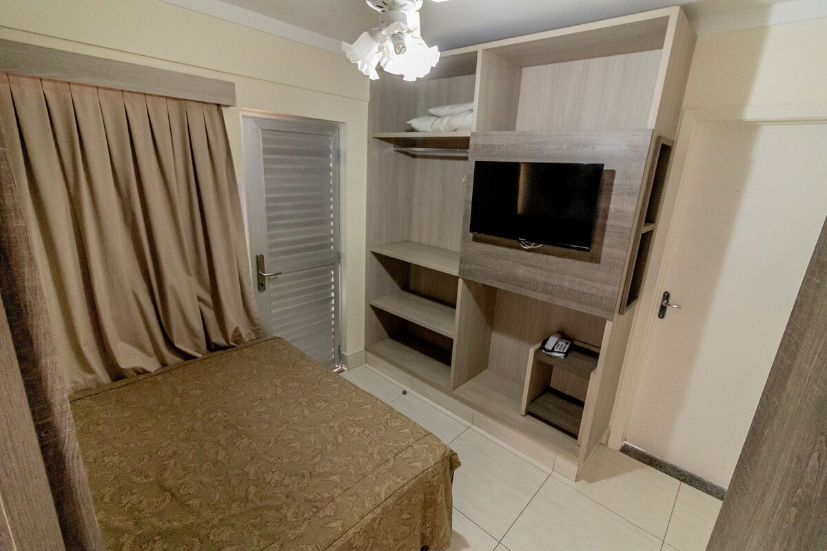 A bedroom with a bed, a TV mounted on a wall, and built-in shelving.