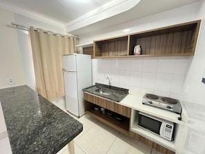 Uma cozinha compacta com geladeira, pia, micro-ondas e fogão.