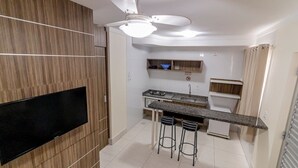 A modern kitchen with a built-in TV, a bar area with stools, and a ceiling fan.