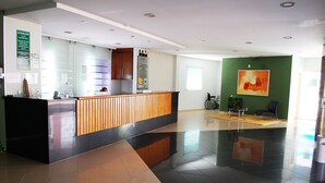 A reception area with a wooden counter, a refrigerator, and a seating area with a bicycle.