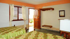 Una habitación con dos camas, una puerta de madera, un pequeño banco, un espejo y un electrodoméstico blanco.