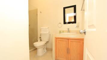 A bathroom with a toilet, sink, mirror, and wooden cabinets.