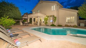 Ein Haus mit Swimmingpool, Gartenmöbeln und einer Terrasse.