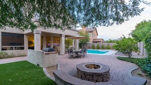 Ein Garten mit Pool, Sitzgelegenheiten im Freien und einer Feuerstelle.