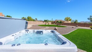 Een jacuzzi in een achtertuin met een helderblauwe lucht, een verzorgd gazon en een verre horizon met huizen.