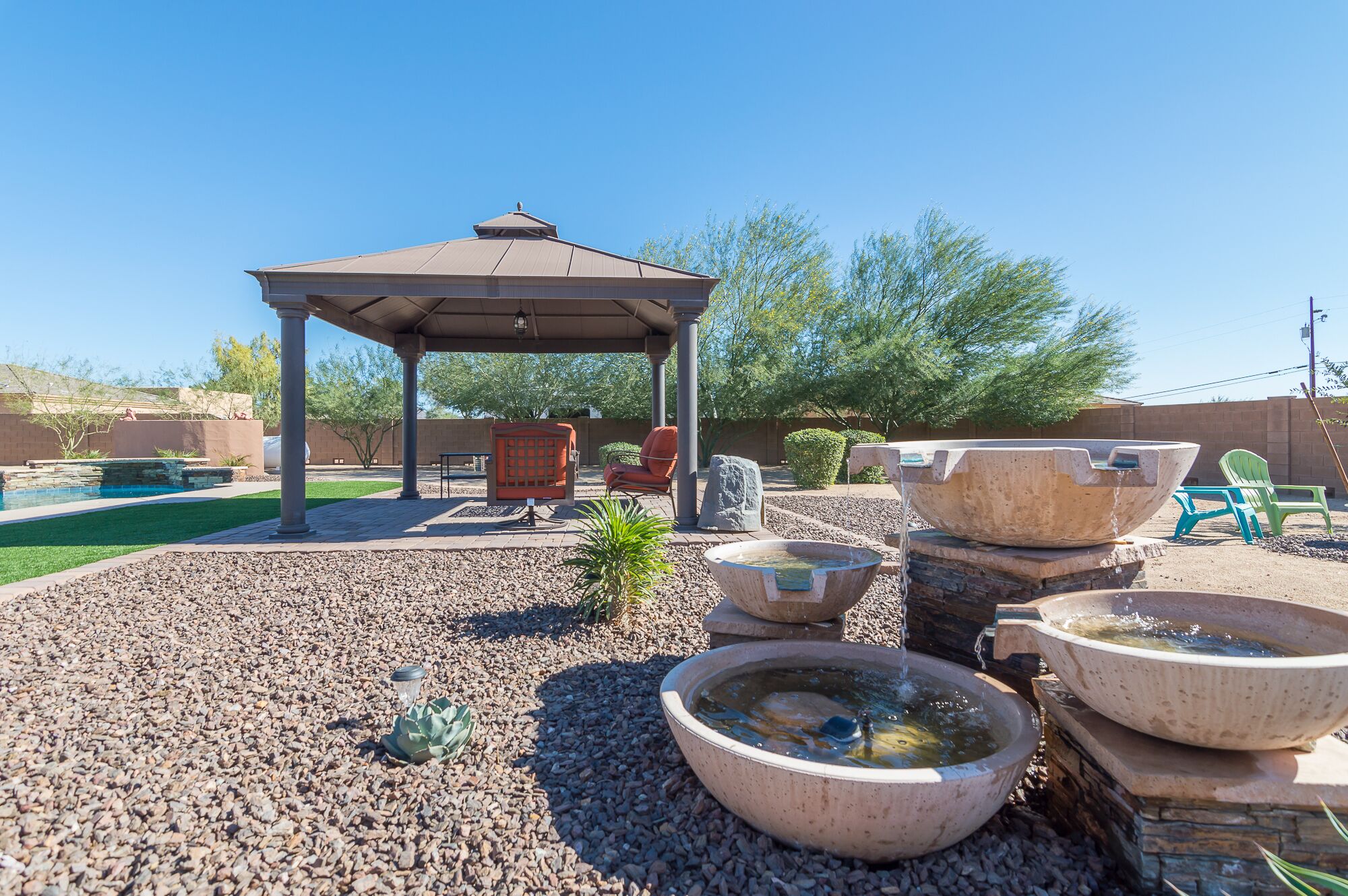 A covered outdoor area with a gazebo, seating, and decorative stone planters.