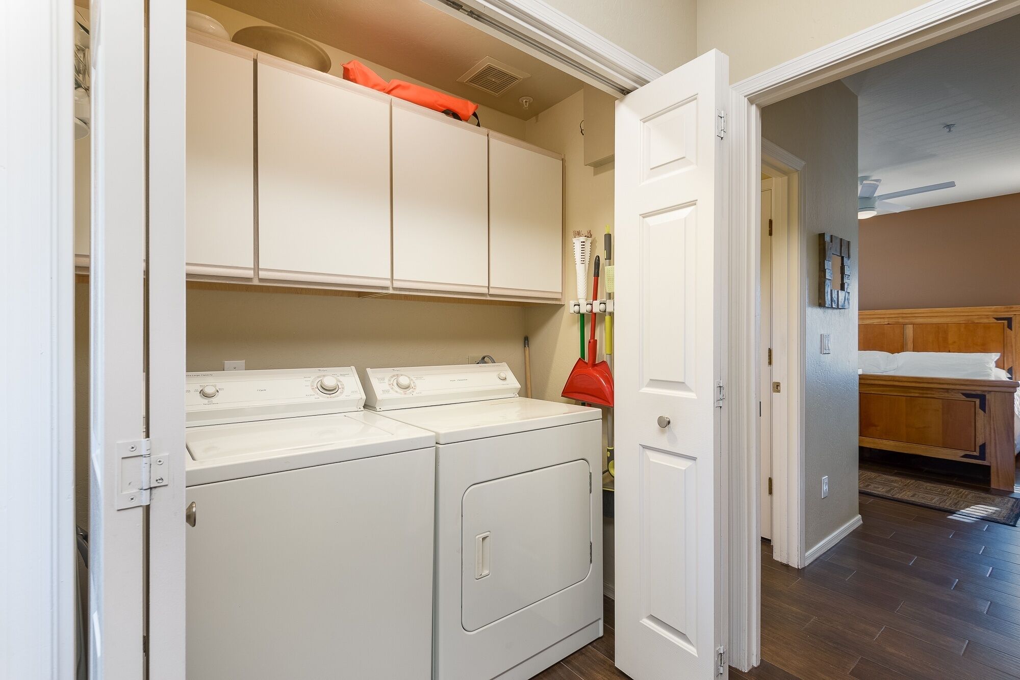A laundry room with a washing machine, dryer, and a broom rack.