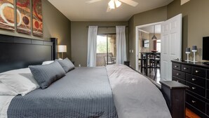 A bedroom with a large bed, a ceiling fan, a desk, and a dining area. - Signature 2 Bedroom Condo by RedAwning (Scottsdale)