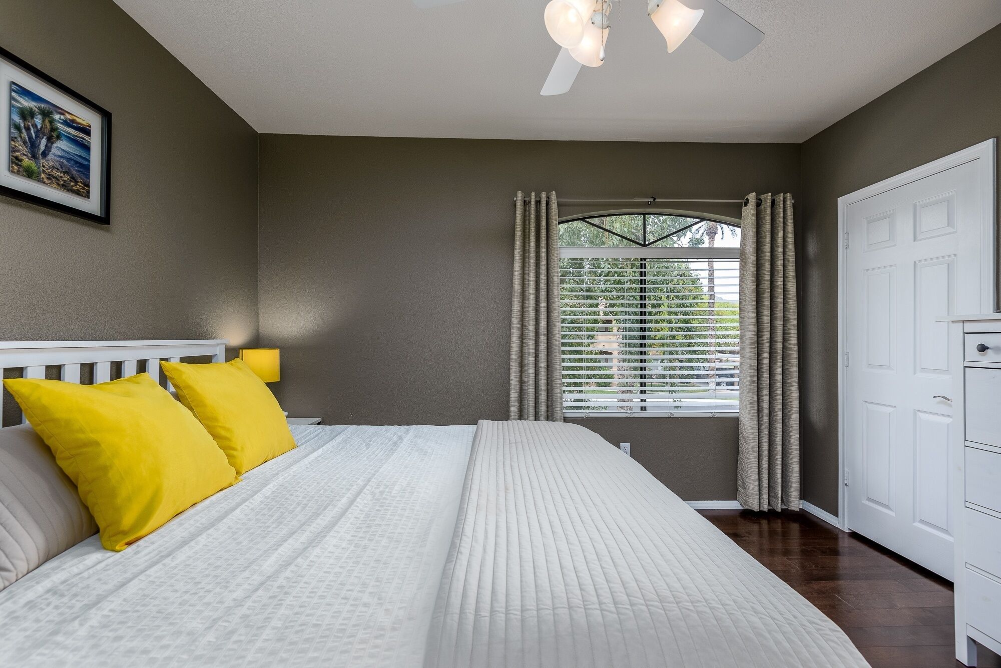 A bedroom with a bed, a nightstand, a window with curtains, and a door.