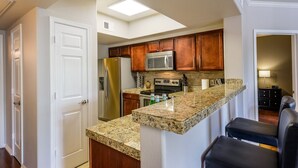 A modern kitchen with granite countertops, stainless steel appliances, and wooden cabinets. - Signature 2 Bedroom Condo by RedAwning (Scottsdale)