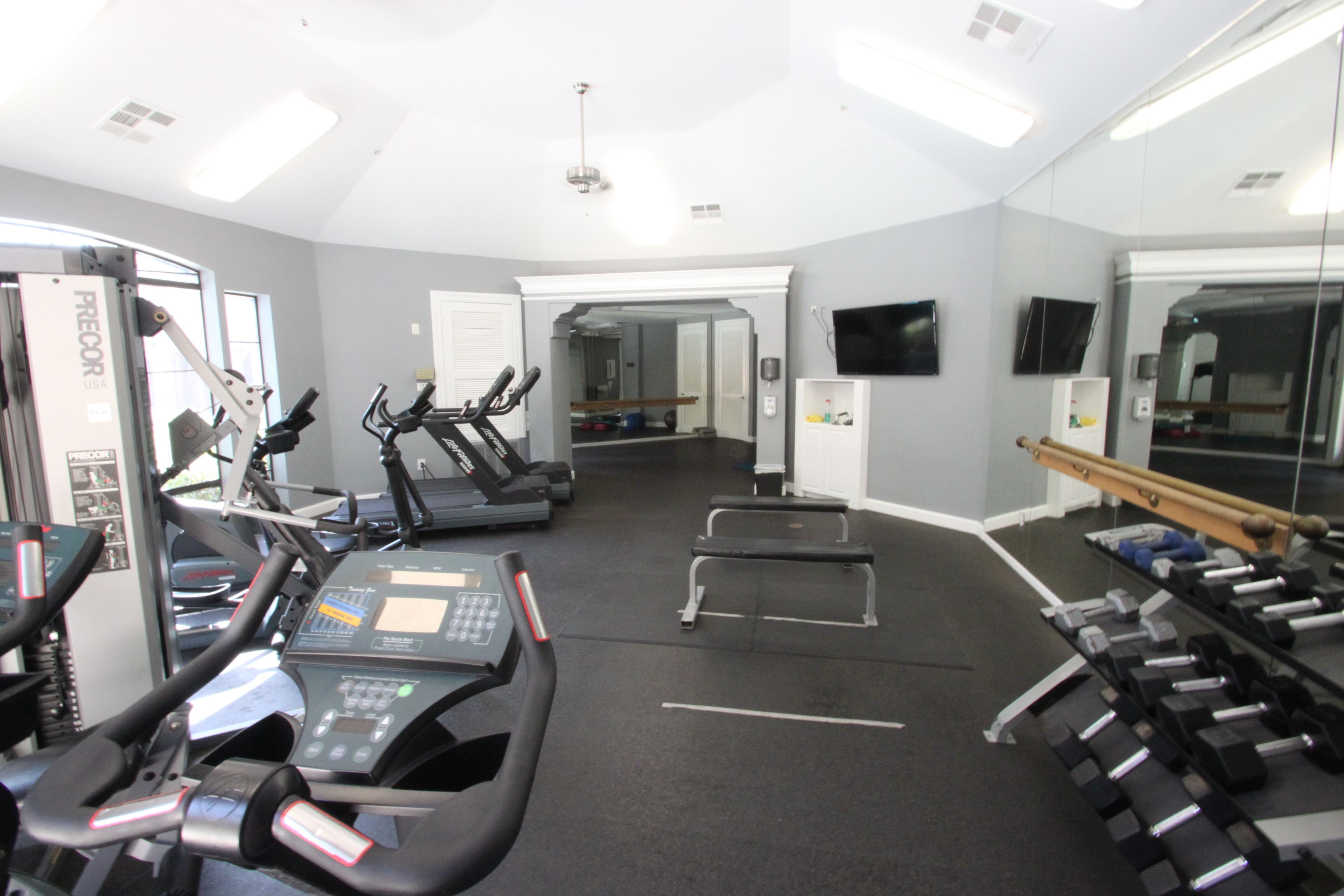 A gym with treadmills, a stationary bike, and free weights.