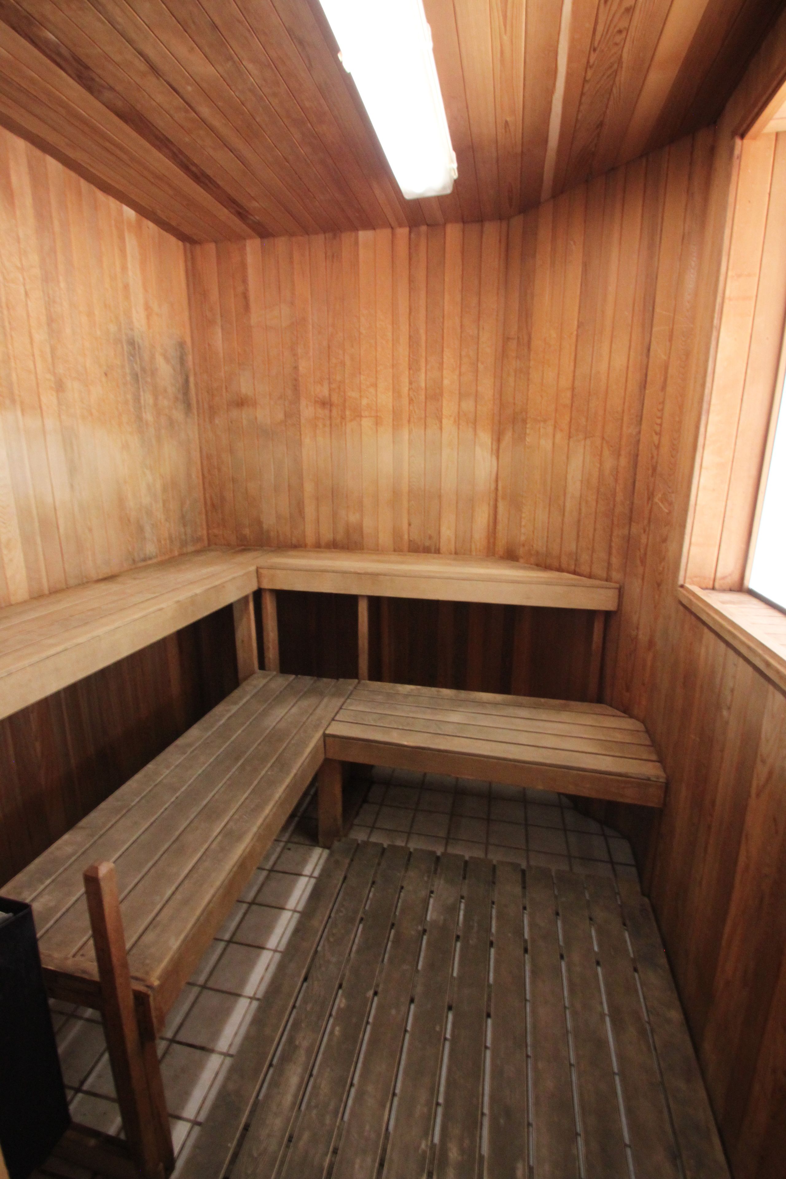 Un sauna avec des bancs en bois et un plancher incliné.