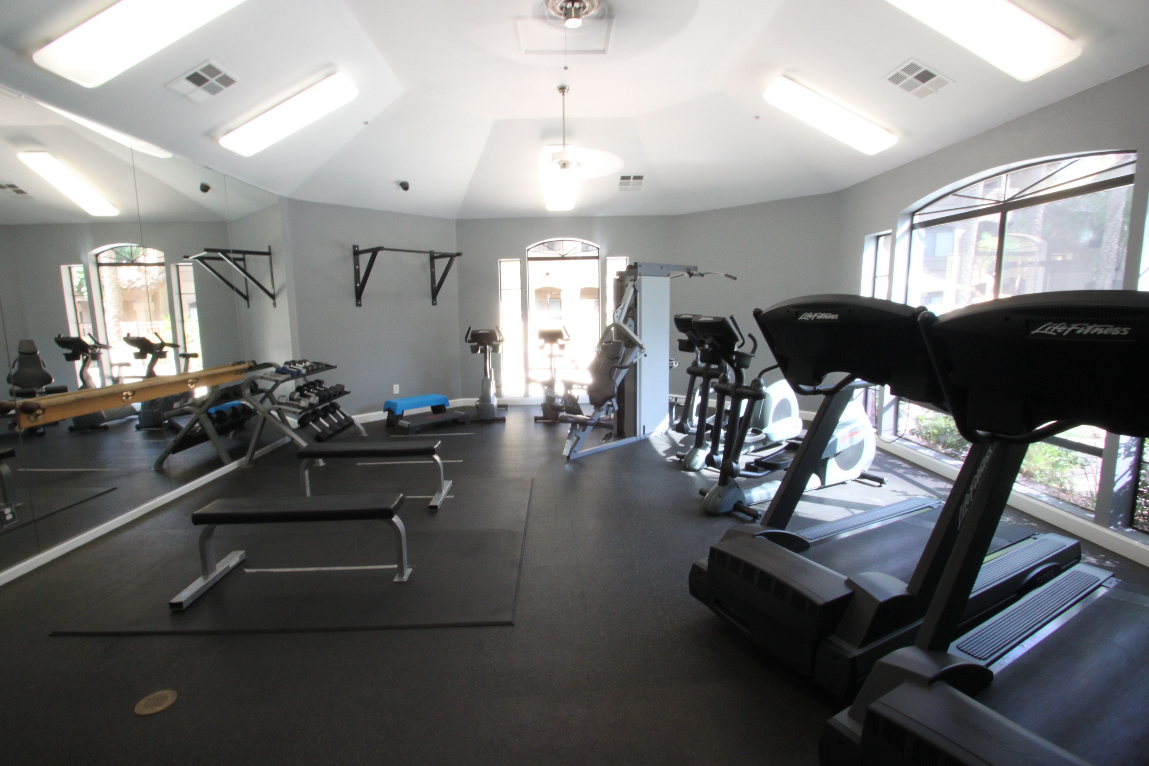 A gym with treadmills, exercise equipment, and large windows.