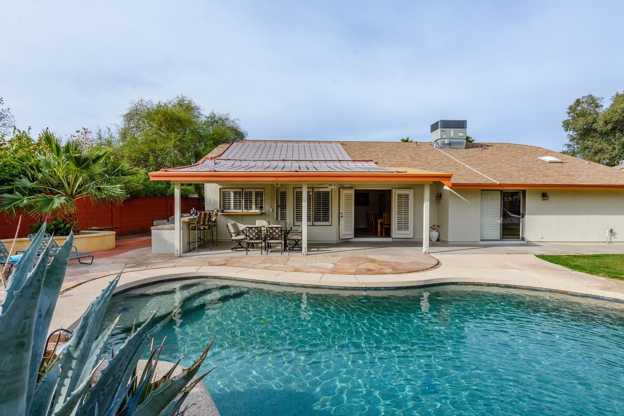 A house with a swimming pool, patio furniture, and a covered outdoor area.