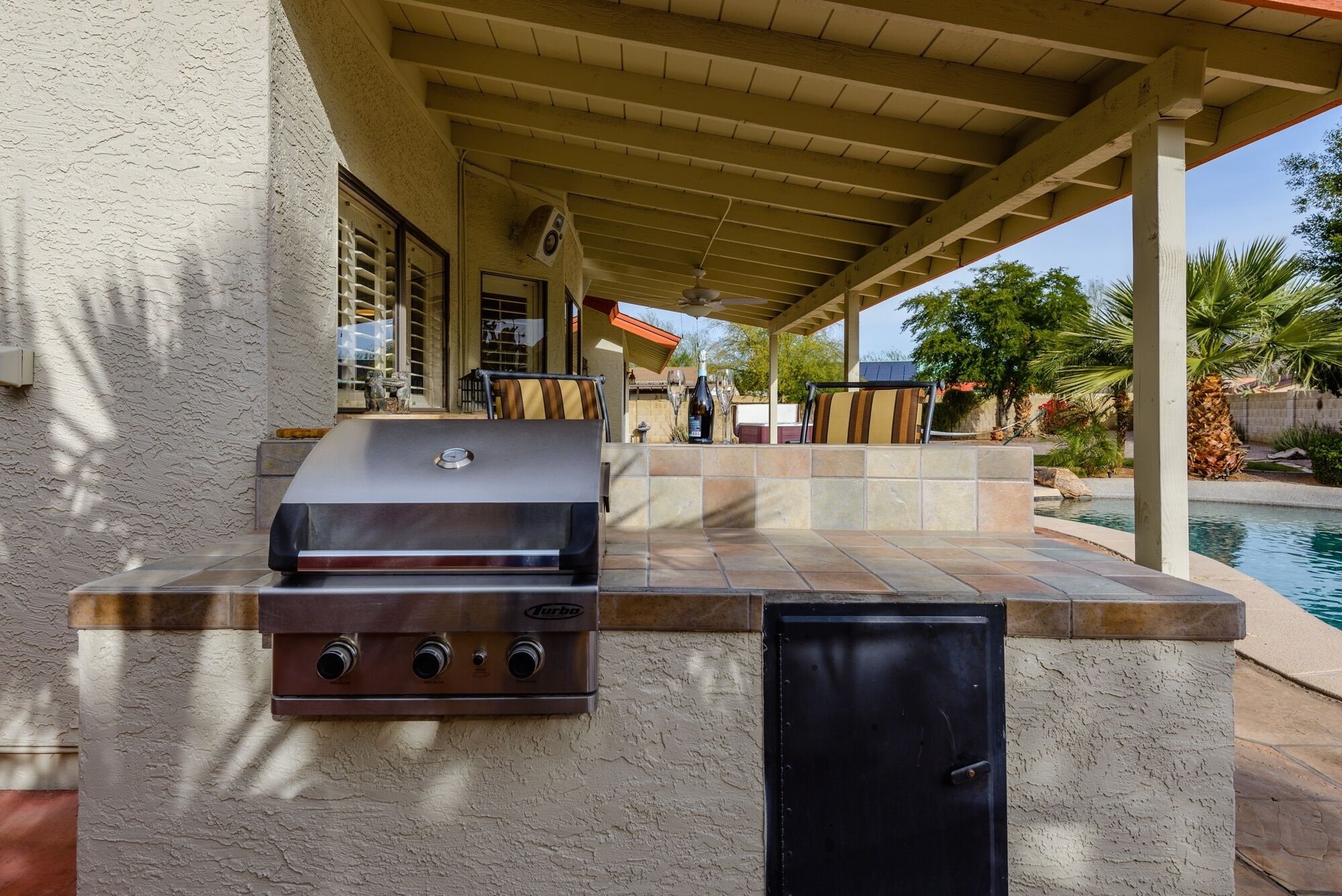 An outdoor patio with a built-in grill and a pool.