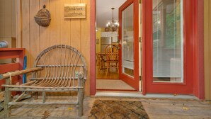 A rustic interior with a wicker bench, a wooden door, and a sign reading "Fernbrook Treehouse". - Hot Tub - Screen Porch - Rockers - Fire Pit - Cozy - Clean - Fast Wi-Fi - 5 Star (Maggie Valley)