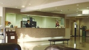 A reception area with a counter, a clock, and a Christmas tree. - Central Hotel Toride (Toride)