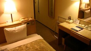A hotel room with a bed, bedside table with a lamp, a desk with a chair, and a mirror. - Central Hotel Toride (Toride)