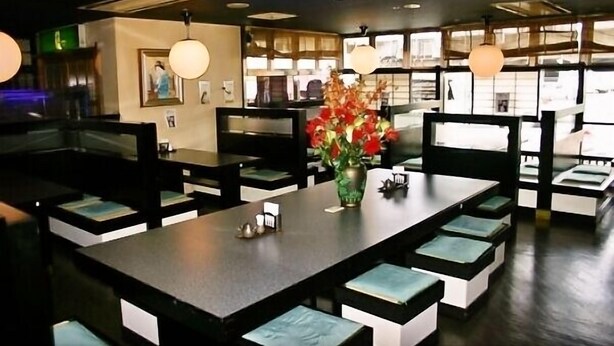 A restaurant with booth seating, pendant lighting, and a vase of flowers on the table. - Central Hotel Toride (Toride)