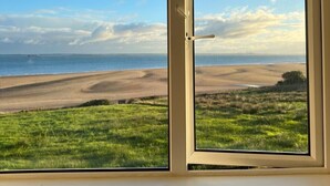 A window with a view of a beach and grassy area. - Stunning Beachfront Cottage  Ballybunion (Ballybunion,)