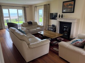 A living room with a sofa set, a coffee table, a fireplace, and a TV. - Stunning Beachfront Cottage Ballybunion (Ballybunion,)