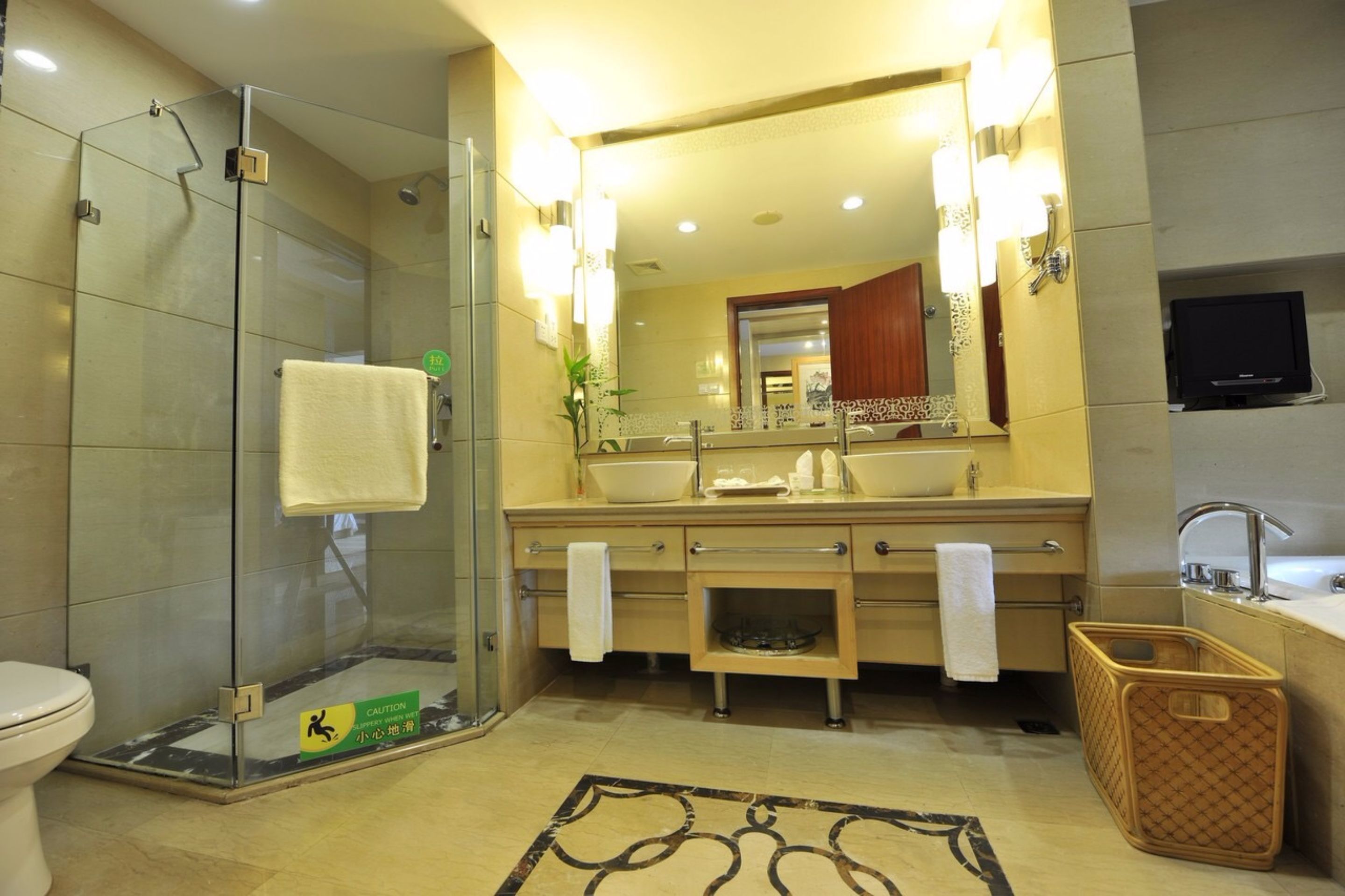 A modern bathroom with a glass-enclosed shower, a large mirror, and a sink with a vanity.