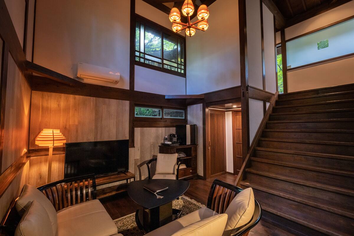 A spacious living area with a sofa, a coffee table, a TV, and a staircase.