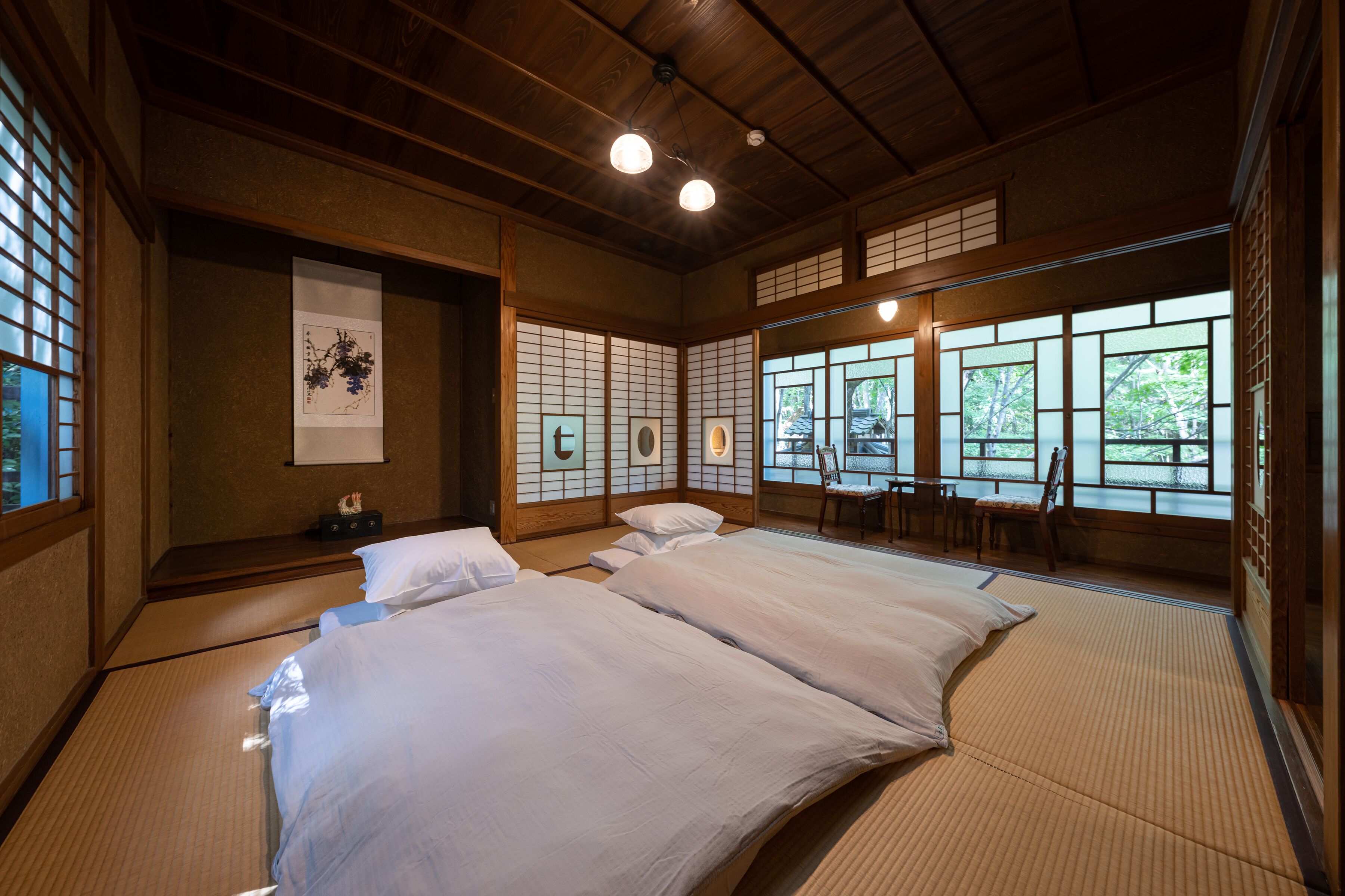 Una habitación tradicional japonesa con suelo de tatami, techo de madera bajo y puertas correderas.