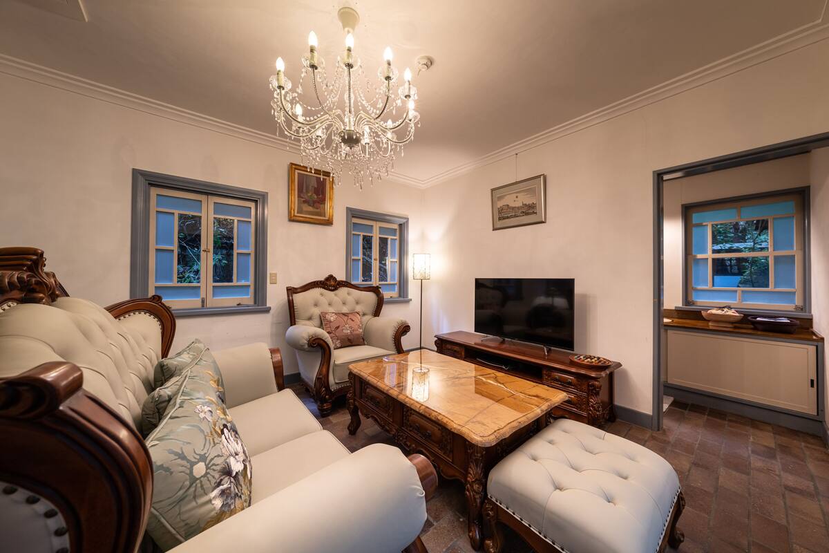 A living room with a chandelier, a television, and a sofa with floral cushions.