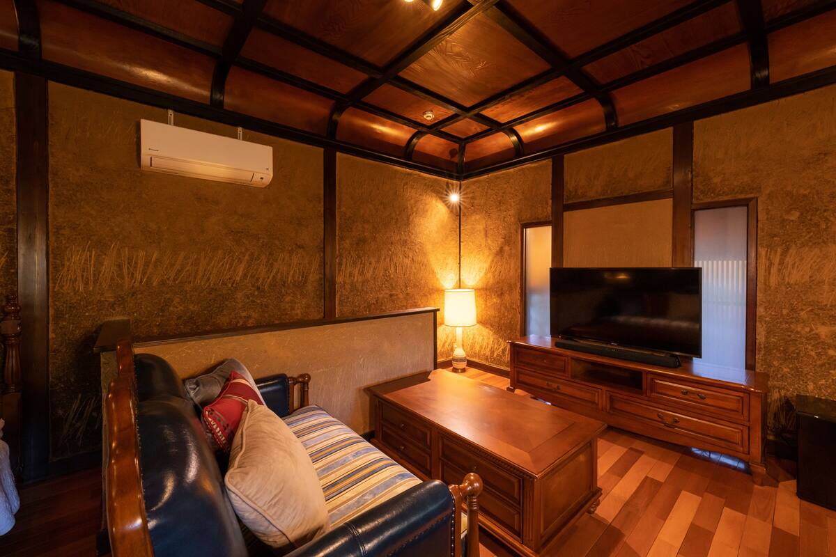 A cozy living room with a leather sofa, a television, and a wooden coffee table.