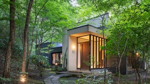 A modern house with a stone pathway leading to the entrance, surrounded by lush greenery. - Nihon No Ashitaba (Yufu)