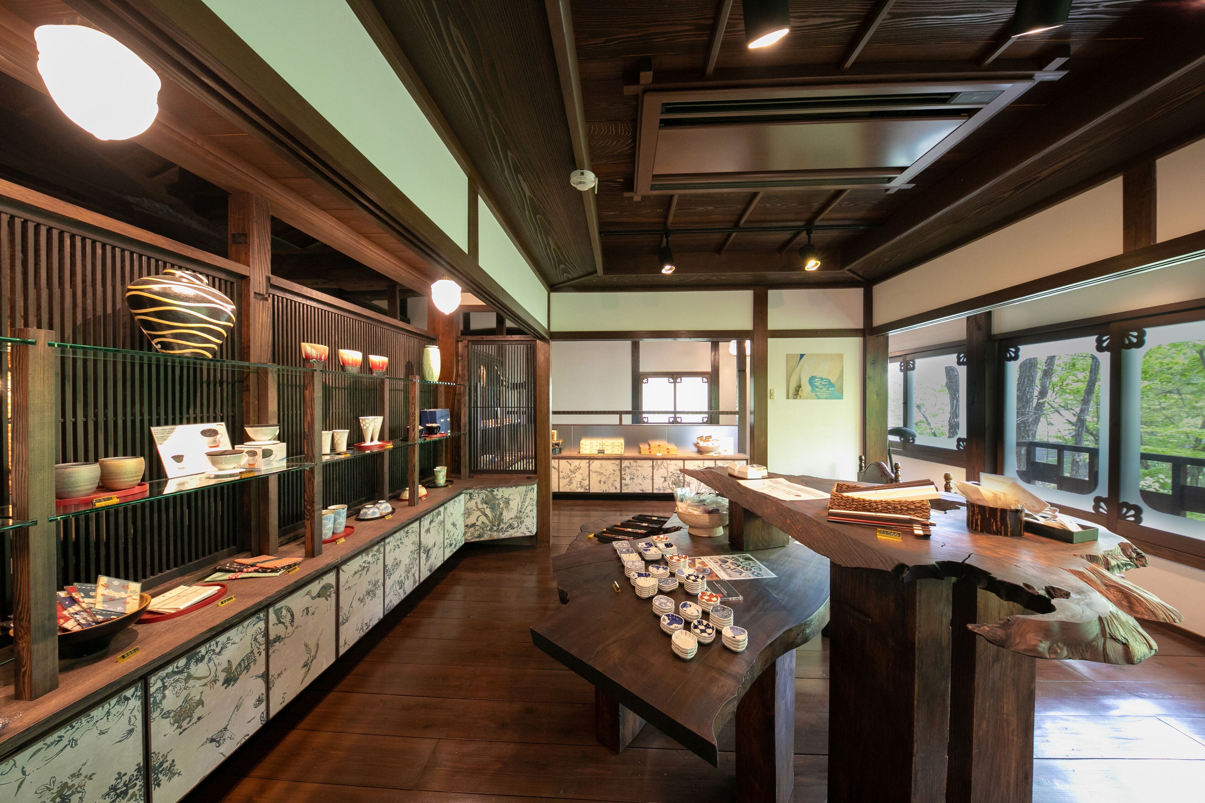 A restaurant interior with wooden beams, a long counter, and a display of bowls and dishes.