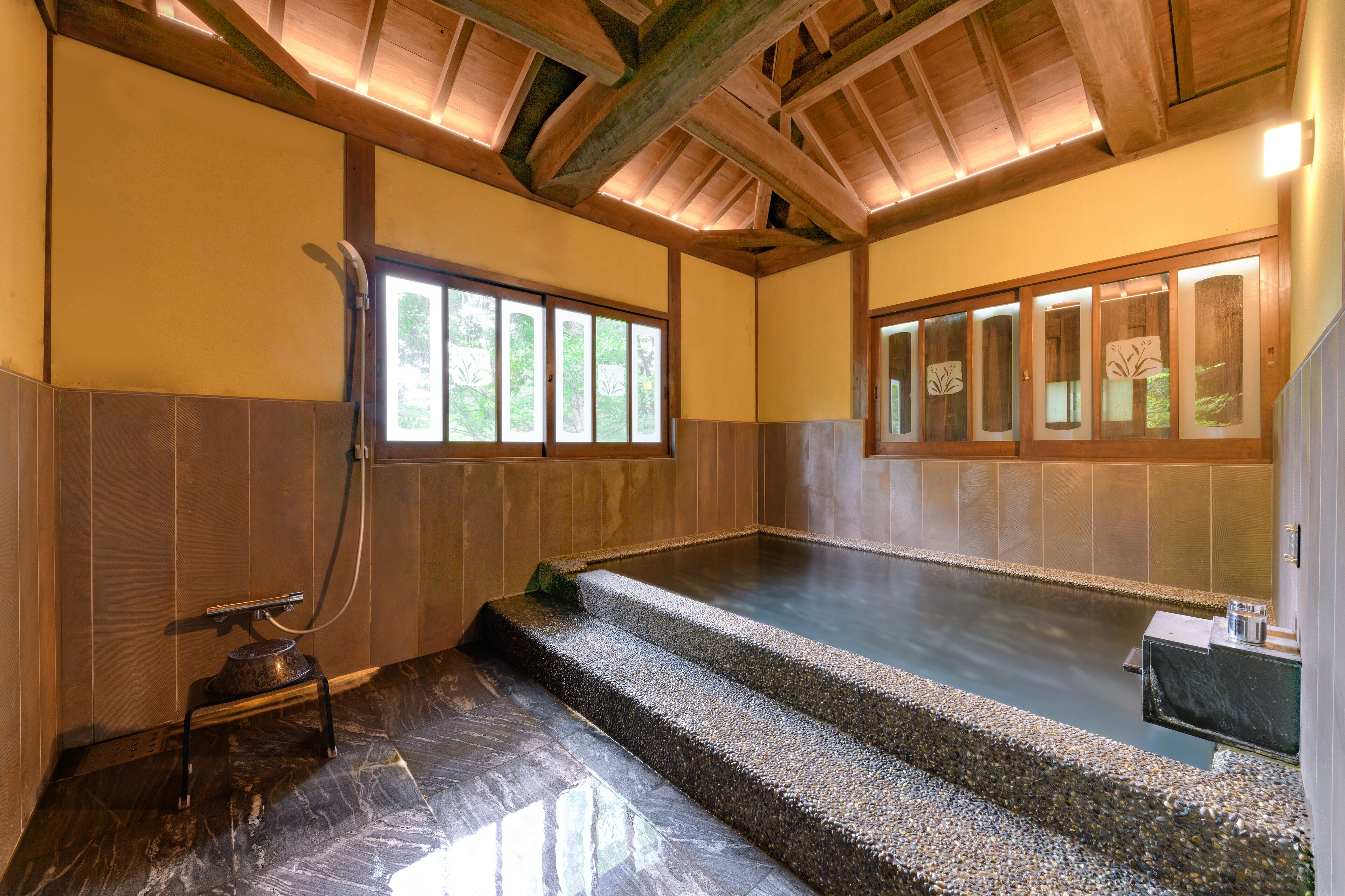 A traditional Japanese onsen with a wooden ceiling, tiled walls, and a stone bath area.