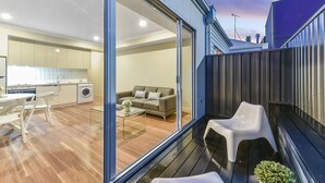 Um apartamento moderno com porta de vidro deslizante que dá para uma sala de estar, uma cozinha e uma varanda com área de estar externa.