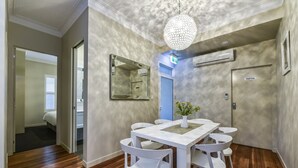 Uma sala de jantar com uma mesa e cadeiras brancas, um lustre pendurado e uma porta com a inscrição 'Apenas para Funcionários'.