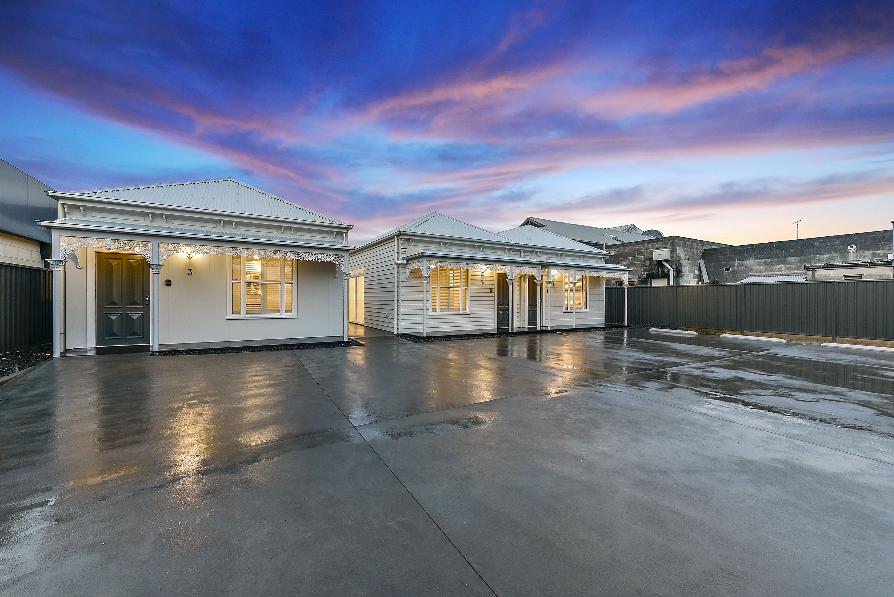 A residential area with two houses featuring a garage and a covered driveway.