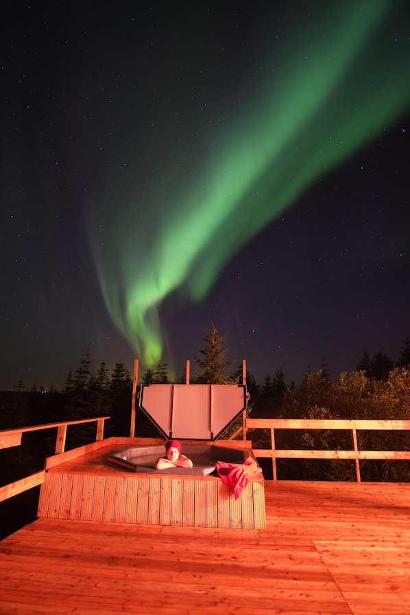 A wooden deck with a hot tub and a person relaxing.