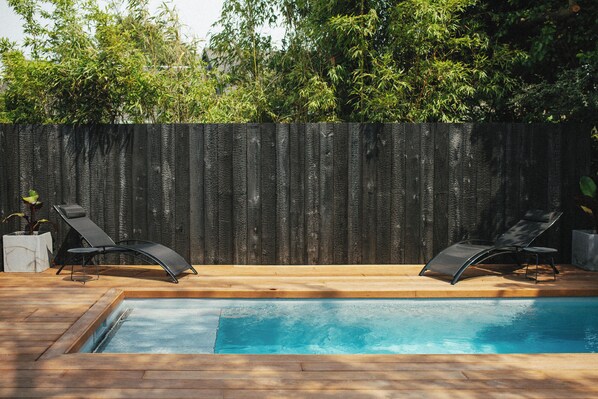 Ein Swimmingpool mit zwei Liegestühlen und einer Holzterrasse.