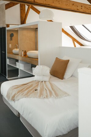 A bedroom with a bed, a white headboard, a brown pillow, and a white bedside table. - A boat house on the beach (Paimpol)