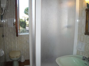 Een badkamer met toilet, wastafel en een raam met uitzicht op groen.