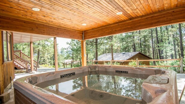 Une cabane en bois avec un bain à remous, un escalier et une vue sur la forêt.