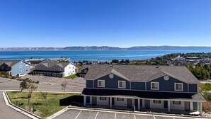 A residential area with houses, a parking lot, and a view of a large body of water with mountains in the distance.