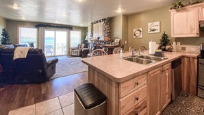 A spacious kitchen with a large island, wooden cabinets, and a view to a balcony.