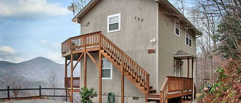 A two-story wooden house with a balcony and a staircase leading to the second floor.