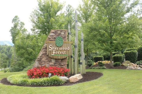 A sign for Sherwood Forest Resort surrounded by landscaped gardens and trees.